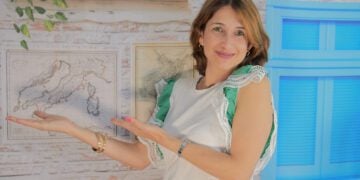 Ana Patrícia em seu escritório com gesto de estar mostrando algo